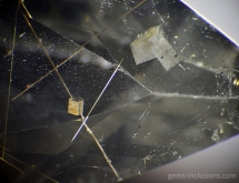 Calcite rhombohedron pierced by rutile needle in quartz